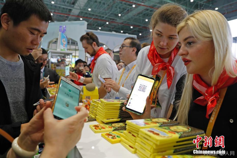 资料图：2018年11月10日，首届中国国际进口博览会食品及农产品展区，参观者扫码支付购买商品。中新社记者 殷立勤 摄
