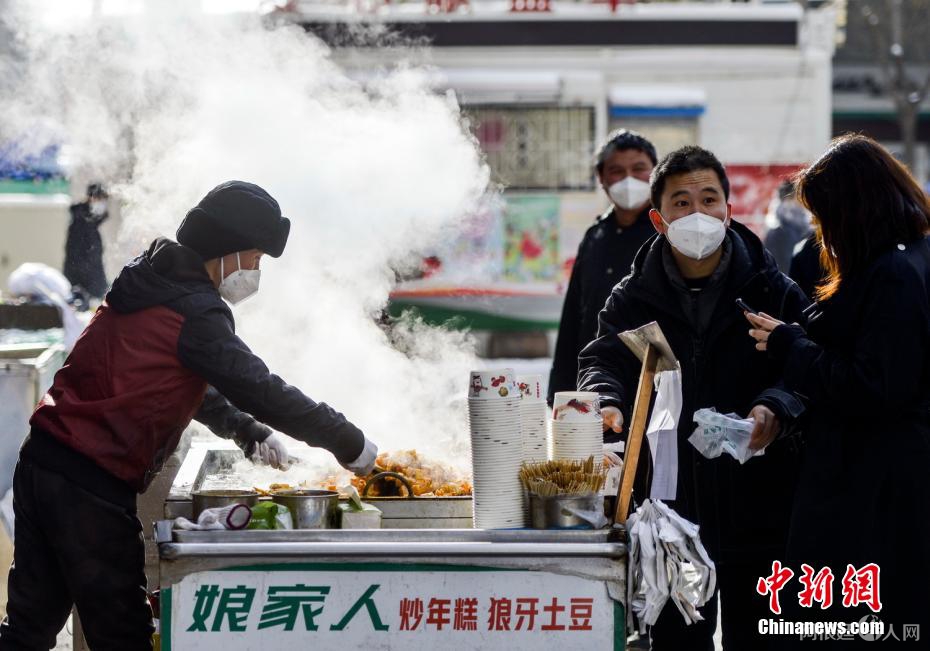 资料图：外出购物的市民购买品尝街头小吃。 刘新 摄