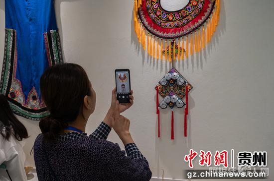 图为9月21日“华文媒体侨行贵州”媒体团记者在毕节市赫章县金银山易地扶贫搬迁社区光彩生活空间拍摄刺绣作品。唐哲 摄