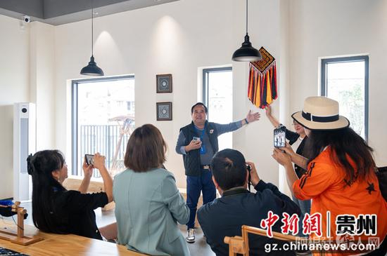 图为9月21日“华文媒体侨行贵州”媒体团一行在毕节市赫章县金银山易地扶贫搬迁社区光彩生活空间刺绣作品前拍照。唐哲 摄
