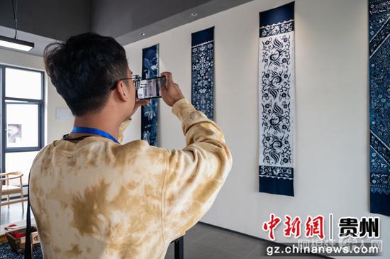 图为9月21日“华文媒体侨行贵州”媒体团记者在毕节市赫章县金银山易地扶贫搬迁社区光彩生活空间拍摄蜡染作品。唐哲 摄